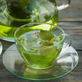 Herbal tea with melissa in a glass cup and teapot