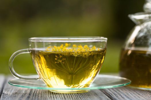 Herbal tea with dill in a glass cup outdoors