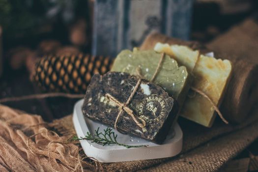 Pieces of beautiful natural handcrafted soap on wooden background with botanical elements, close up view. For relax, health, spa and aromatherapy