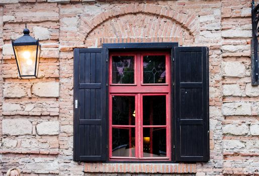 Retro window with black jalousie outdoor and old brich wall