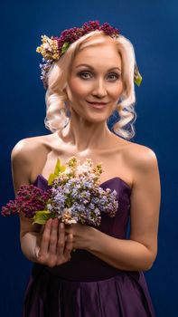 Drunk beautifully youthful in a lilac wreath with a Caucasian appearance overjoyed. on a blue background, happy day best