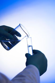 Male scientist pours liquid from beaker into test tube