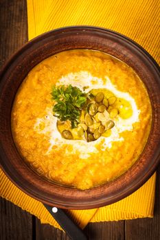 Pumpkin soup in clay bowl with spoon on the table