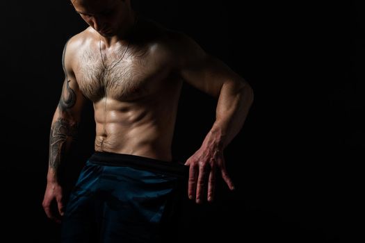 Man on black background keeps dumbbells pumped up in fitness sexy black, arm training workout lifting dumbbell, pectoral. handsome power, people fit Look at the press and measures the size of pants for weight loss, lovely press