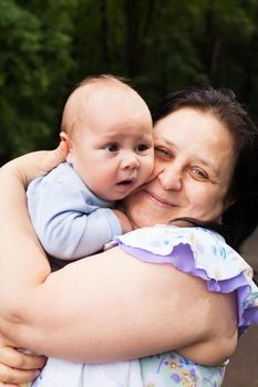 Grandmother with her little grandson in a park. Family portraits