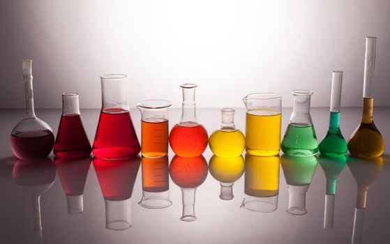 Laboratory glass with rainbow color liquids, chemistry still life