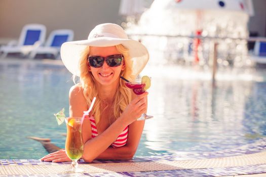 Blonde woman in hat at the swimming pool