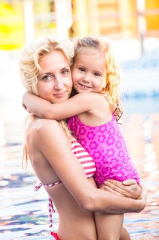 Mother is teaching her daughter to swim at the swimming pool