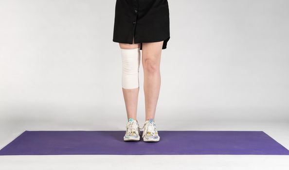 Bandage on the leg on a white background, on a purple mat in a black skirt girl