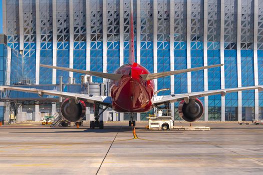 Airplane is parked near gate of airport terminal on sunny day