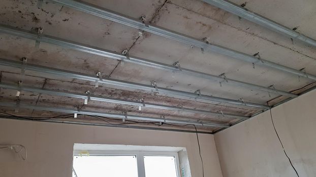False ceiling design, before installing drywall. Plasterboard ceiling of a house at a construction site, installation of a false ceiling in a square room.