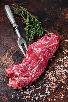 Uncooked Raw flank beef steak on meat fork. Dark background. Top view.
