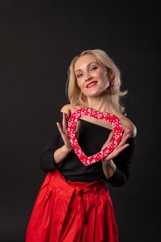 Girl holding a heart at eye level valentine , valentine design, romantic hearts on the floor . February 14 banner. emotions forever, joy in a red dress girl, barefoot