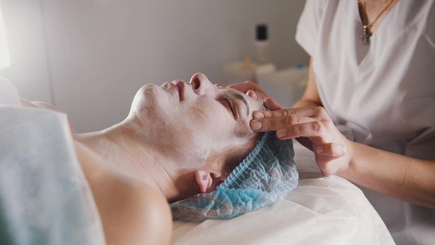 Woman getting a cosmetic procedure - mask facial massage at spa salon skincare, close up