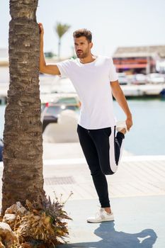 Young man stretching after exercise in a harbour