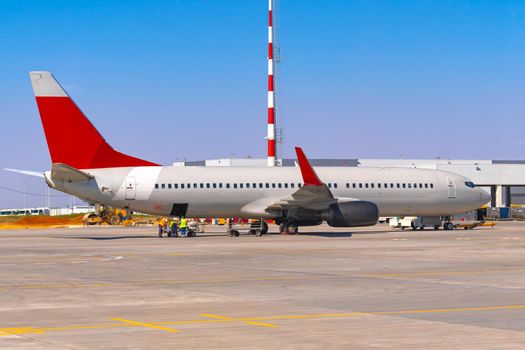 Airplane is parked near gate of airport terminal on sunny day