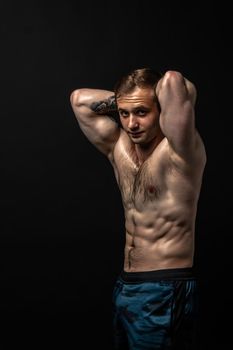 Man on black background keeps dumbbells pumped up in fitness chest training strong dumbbell, shirtless lifestyle. Attractive gym fit hands behind your head a beautiful press