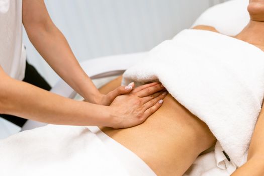 Middle-aged woman having a belly massage in a beauty salon. Body care treatment in a beauty centre.