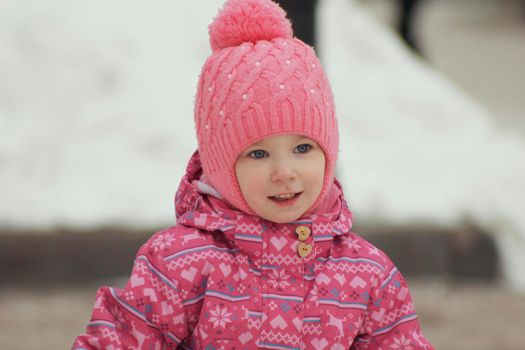 Portrait of a cute little girl having fun in snow park, close up