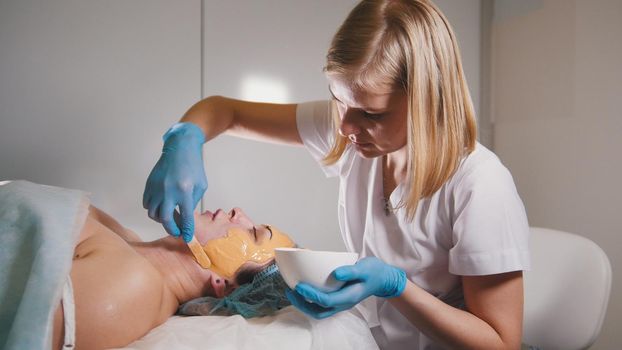 Young woman passes treatment fruit mask facial at the beauty salon, close up