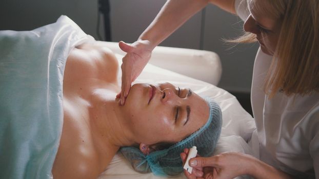 Cosmetologist massaging client's face in the beauty salon, beauty and self-care concept