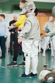 Young participant of the fencing tournament with rapier in his hands, telephoto shot