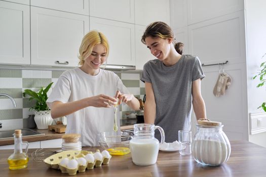 Teenagers guy and girl cooking pancakes in kitchen together. Young people, couple of friends, learning to cook, laughing, talking. Hobbies, teens, emotions, lifestyle, cooking concept