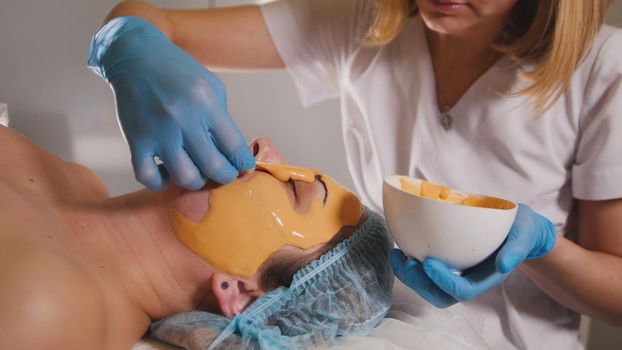 Woman passes treatment fruit mask facial at the beauty salon, close up