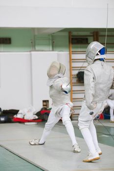 Two young fencers fighting on the fencing competition, telephoto shot