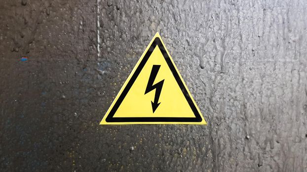 safety sign yellow and black on a silver metal background. High voltage lightning in a triangle caution caution danger electricity death