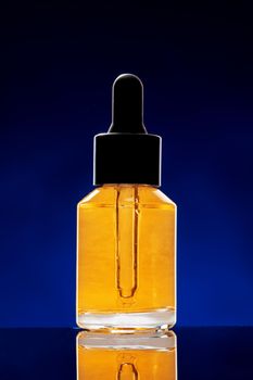 Glass bottle with cosmetic oil on dark background close up