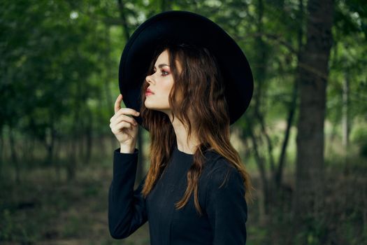 woman witch in black hat in the forest posing fantasy. High quality photo