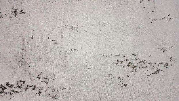 old shabby wall with cracks and chips with whitewash and exfoliated plaster, putty. Vintage gray textured putty on the wall. Rough grunge wall background