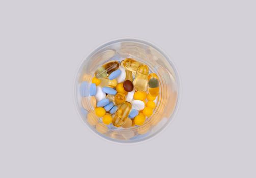 Dose of the colored pills in the glass of the package of pills. On white background with copy space for text.