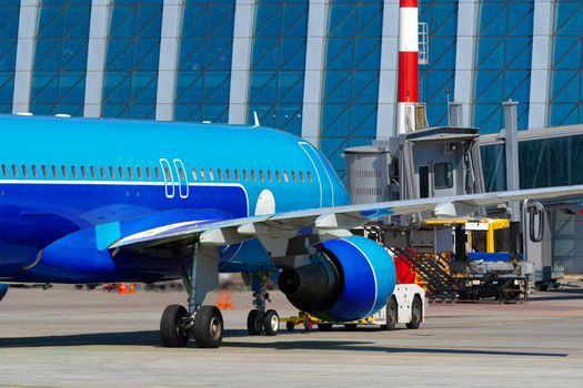 Airplane is parked near gate of airport terminal on sunny day