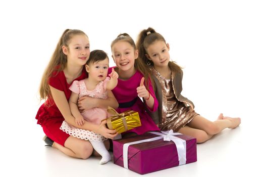 A company of little girls sits on the floor near gifts. Separate on a white background. The concept of family holidays, new year.