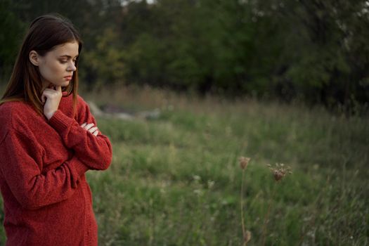 woman in a red sweater outdoors in a field walk. High quality photo