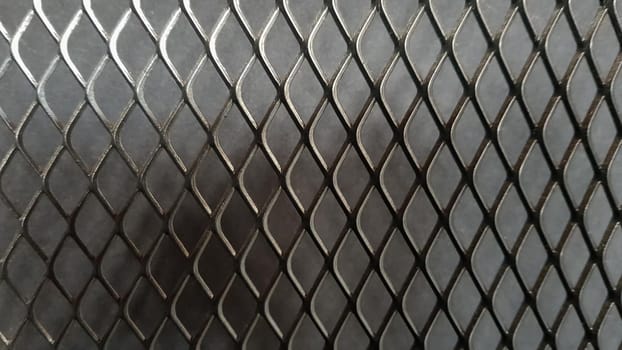 Metal mesh seamless pattern. Black metal mesh texture on a black background. Bulletin board for text and message design. Rhombus shape.
