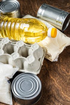 Food delivery Donation, quarantine help concept. Oil, canned food, pasta, bread, sugar, egg. Wooden background. Top view.