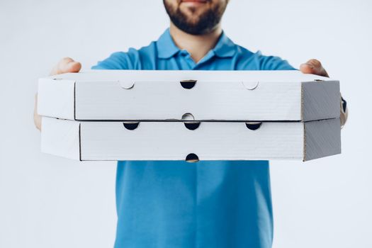 Unrecognizable man in blue polo shirt with food delivery orders against light grey background