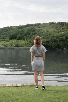 Nature and travel concept. Back view of a woman standing near the lake