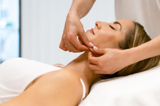 Middle-aged woman having a head massage in a beauty salon. Body care treatment in a beauty centre.