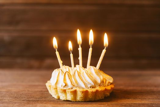 Birthday cupcake with five candles on a wooden background.