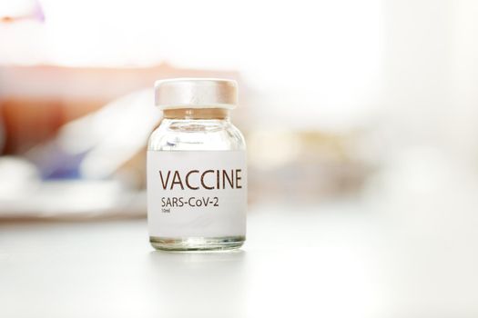Vial of Covid-19 coronavirus vaccine on table in medical lab close up