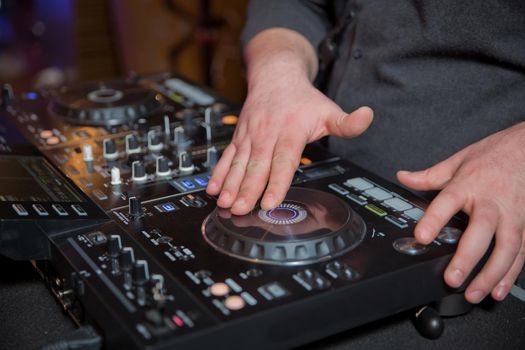 DJ playing music at mixer closeup . Close up of DJ hands mixing music at electronic party festival . professional music equipment for mixing music in nightclub with hand of DJ