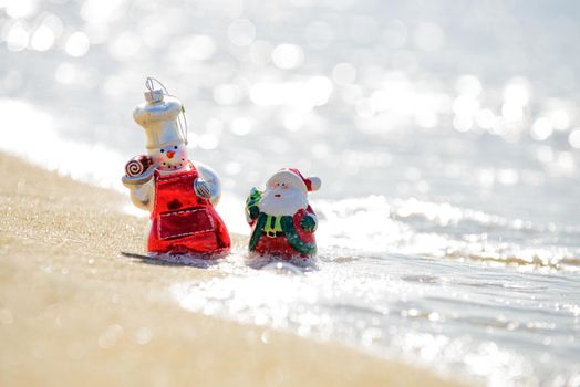 Snowman and santa claus on sea beach. Christmas and New Year's vacation in hot countries