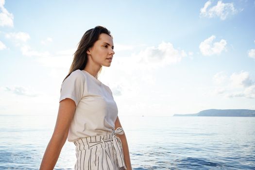 Young brunette woman standing on the nose of the yacht at a sunny summer day, close up