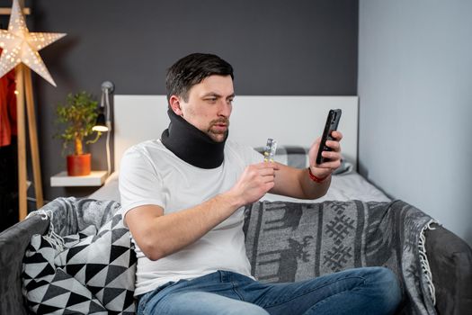Man after accident in cervical collar consults online video call with doctor and receives recommendations for taking medications. Male in foam cervical spinal injury video conferencing with insurance.