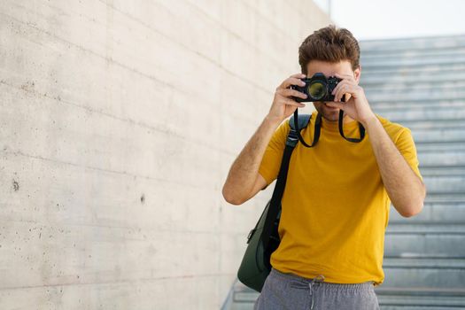 Millennial man taking photographs with a SLR camera outdoors