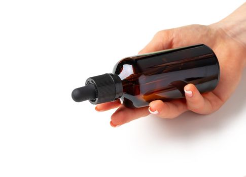 Female hand holding cosmetic bottle on white background